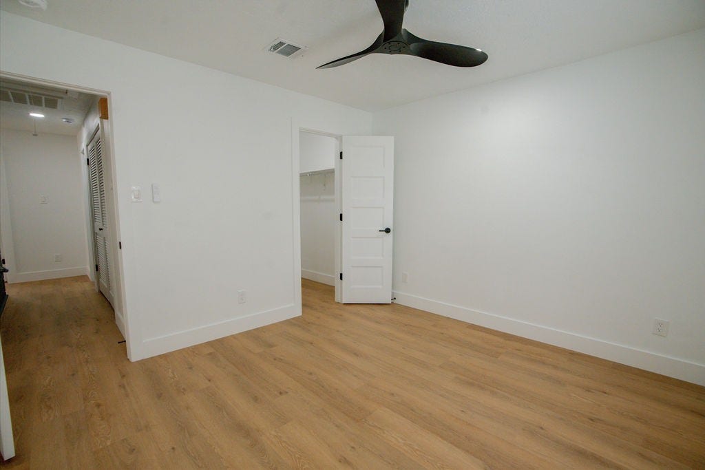 Bright and inviting room with sleek vinyl floors, a modern ceiling fan, and a spacious walk-in closet.