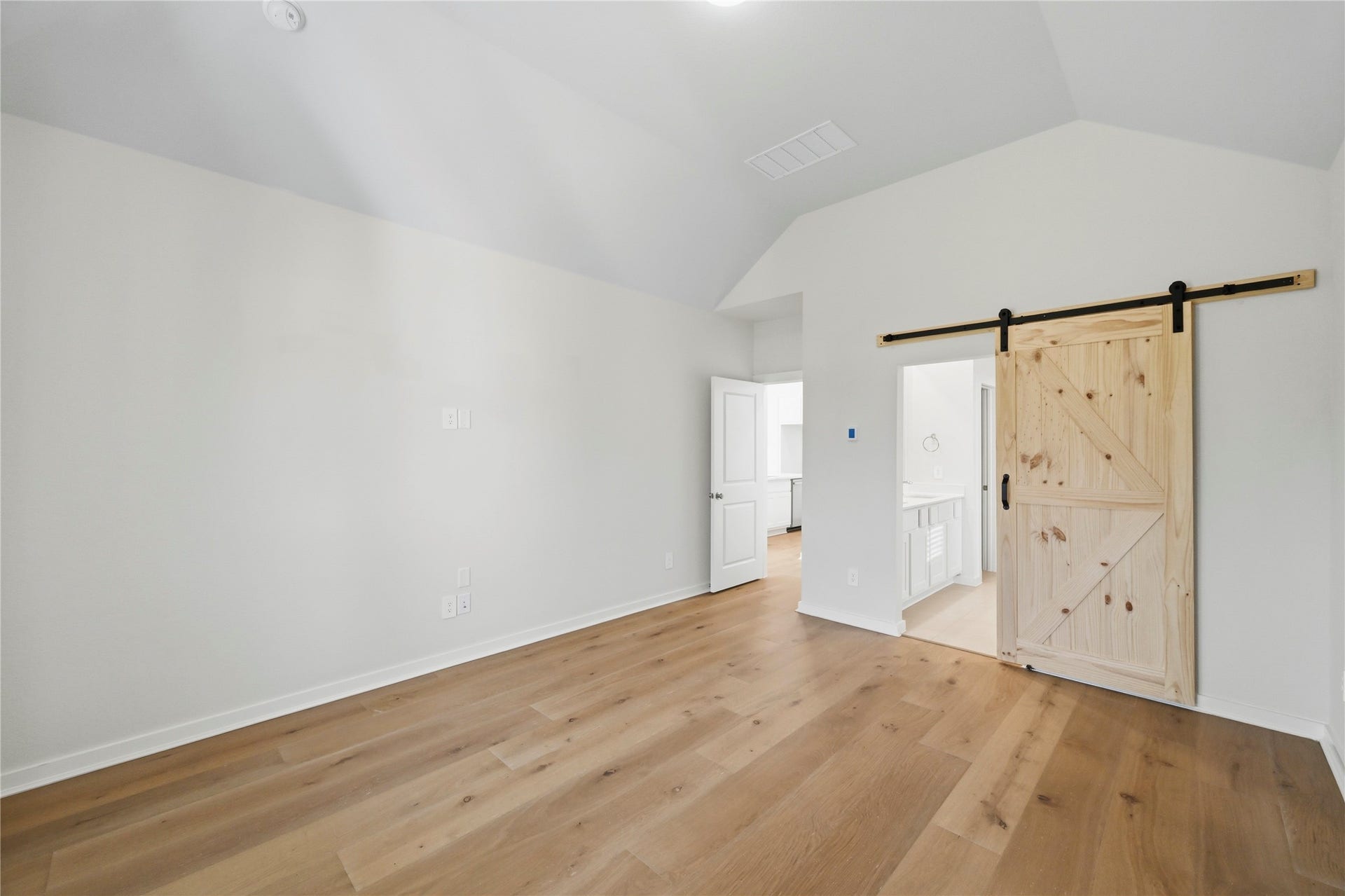 29821 Ellwood Lane, Fulshear, TX 77441 Another view of the primary bedroom featuring a custom sliding barn door leading to the ensuite bathroom.