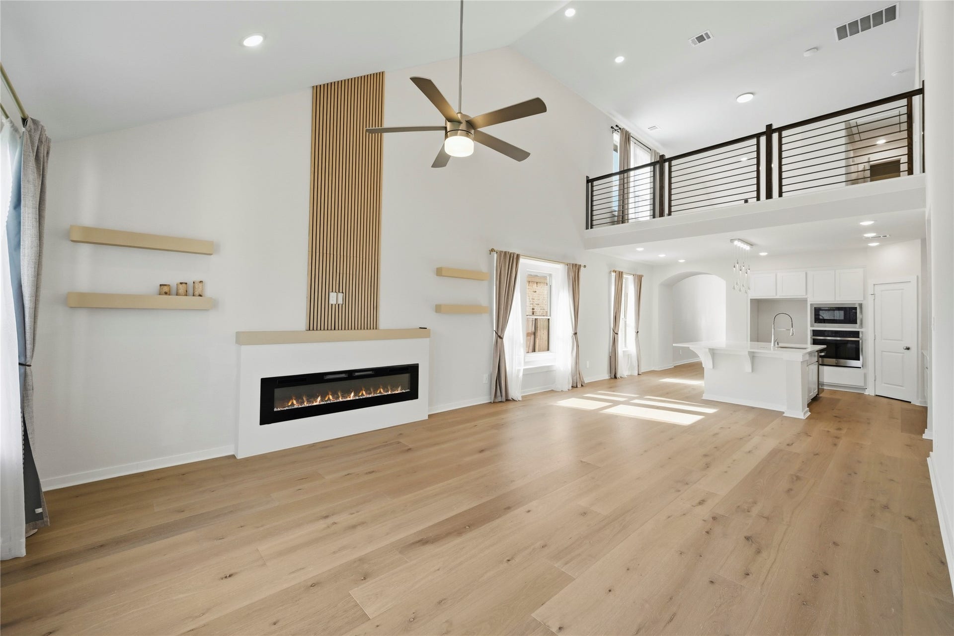 29821 Ellwood Lane, Fulshear, TX 77441 Spacious family room showcasing a striking fireplace feature wall and views of the upstairs loft.