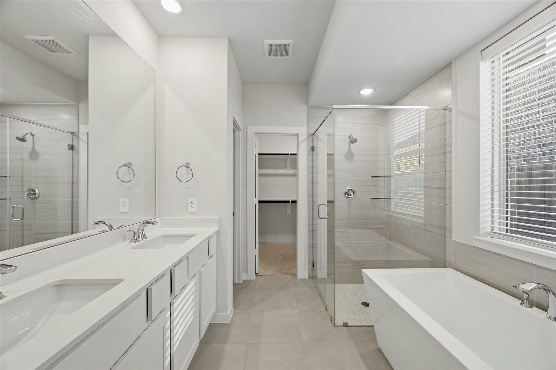 29821 Ellwood Lane, Fulshear, TX 77441 Primary ensuite bathroom featuring dual vanities, a freestanding soaking tub, a frameless glass shower, and a spacious walk-in closet.