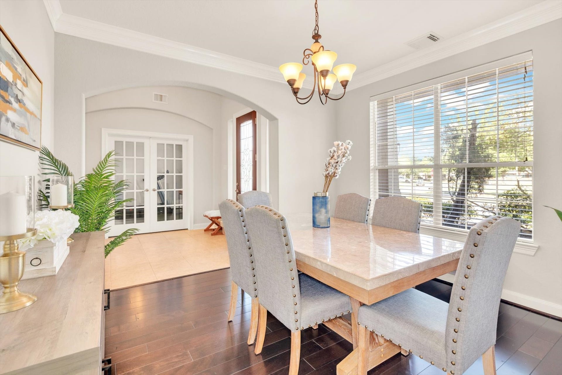 This elegant dining room features a large window for natural light, a stylish chandelier, and a spacious table with comfortable seating.