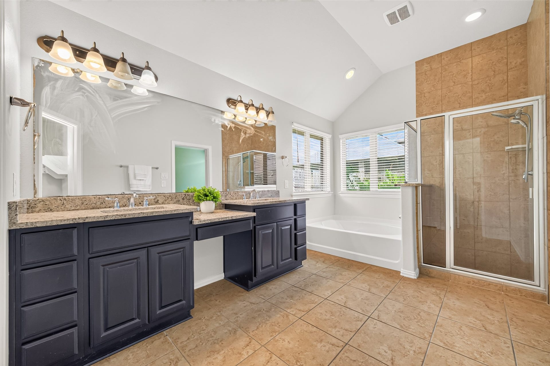 8155 Laughing Falcon Trail, Conroe, TX 77385 Spacious primary bathroom featuring two separate vanities, granite countertops, a dedicated makeup area, and a large wall mirror.