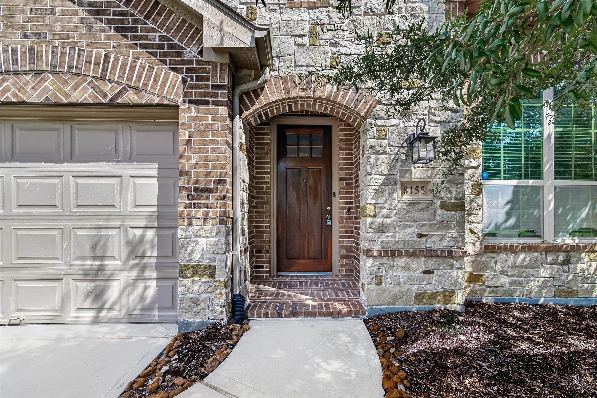 8155 Laughing Falcon Trail, Conroe, TX 77385 Covered front entry with a warm wood-look door, decorative glass panels, and a welcoming approach to the home.