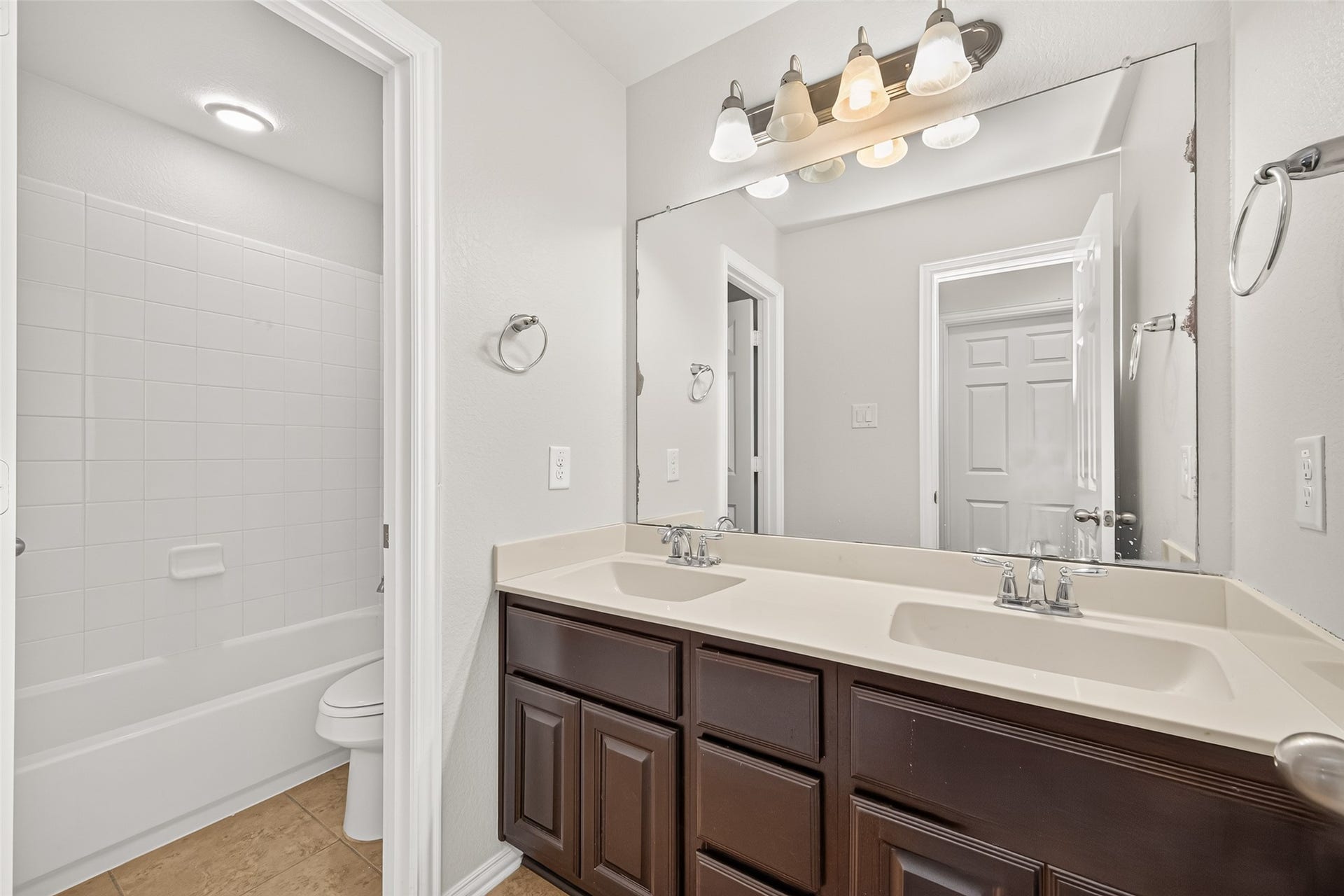 8155 Laughing Falcon Trail, Conroe, TX 77385 Secondary Bathroom. Full secondary bathroom with a double-sink vanity, dark cabinetry, a large wall mirror, and a separate tub-and-shower area.