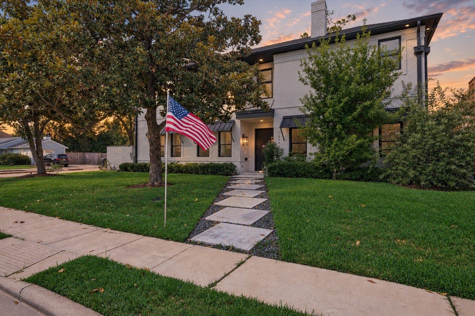 1601 Pine Chase Drive, Houston, TX 77055 Stunning exterior featuring painted brick, sleek metal window awnings, dark trim accents, mature trees, and a custom paver walkway