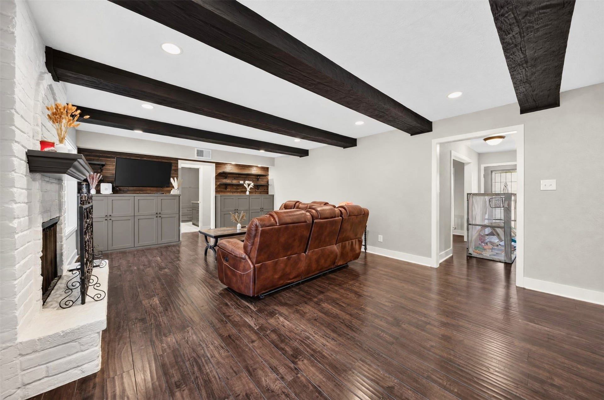 10818 Creektree Drive, Houston, TX 77070 Spacious Living Room
Expansive living room showcasing beautiful wood flooring, dramatic exposed ceiling beams, a painted brick fireplace, recessed lighting, and custom built-in cabinetry with wood accent details.