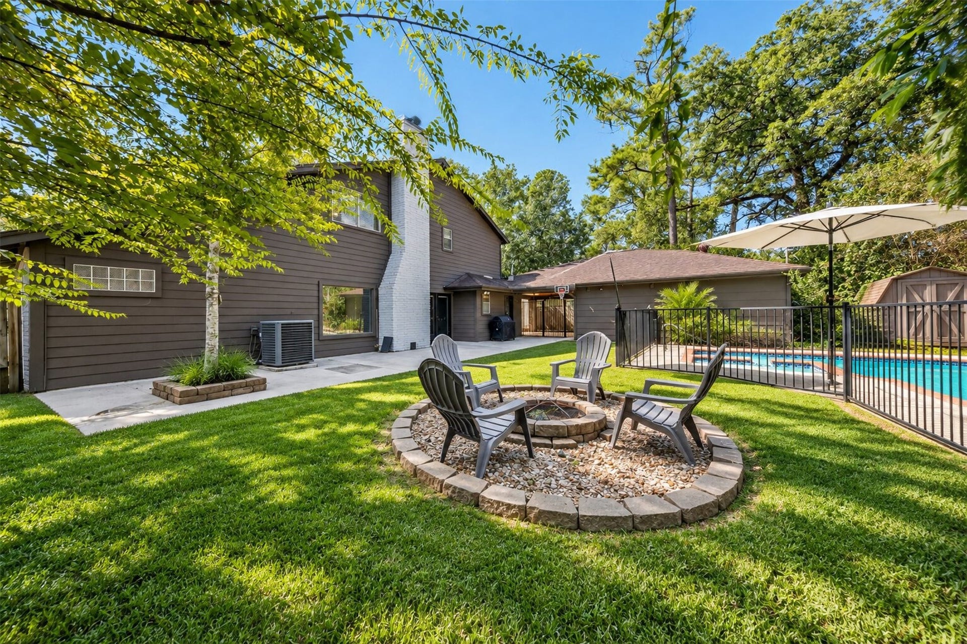 10818 Creektree Drive, Houston, TX 77070 Backyard Retreat: Expansive backyard featuring lush green lawn, mature shade trees, a dedicated fire pit seating area, and a private fenced pool.