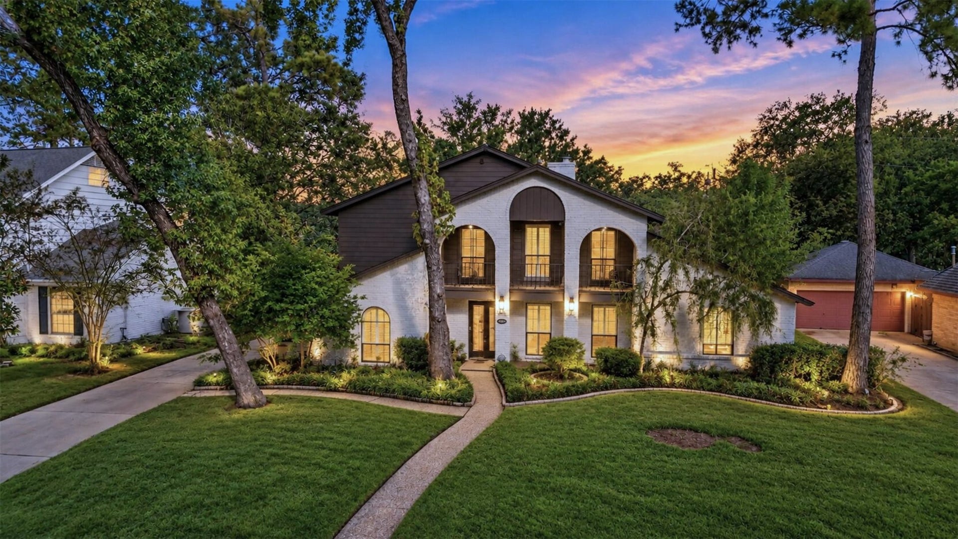 10818 Creektree Drive, Houston, TX 77070 Twilight Front Exterior: Stunning twilight view showcasing the home's distinctive architecture, arched windows, second-story balcony, and beautifully landscaped front yard.
