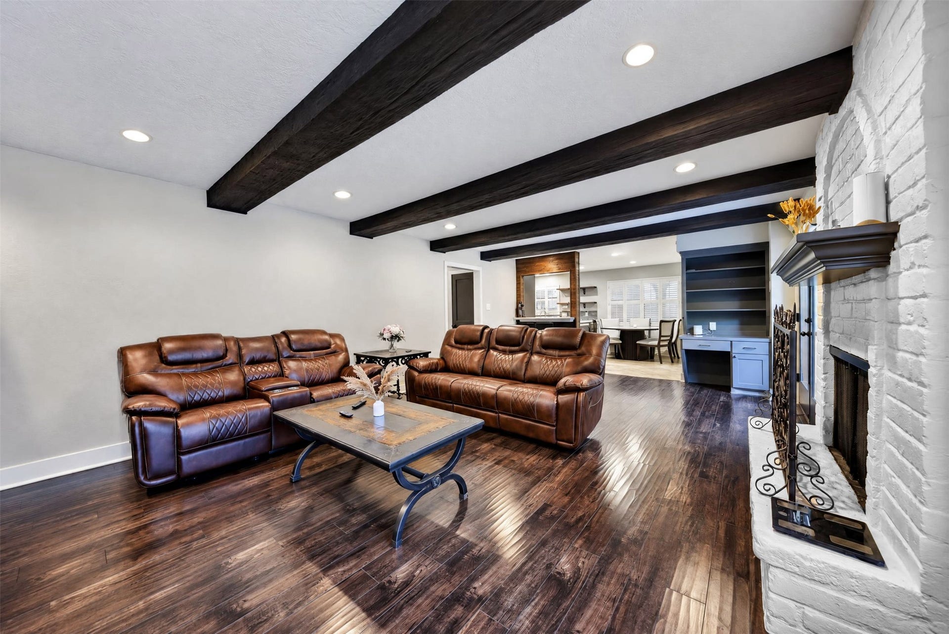 10818 Creektree Drive, Houston, TX 77070 Living Room / Additional View
Expansive living room showcasing striking exposed wood beams, rich wood-look flooring, and a beautiful white brick fireplace. The open design creates an inviting atmosphere with seamless access to the adjoining breakfast area.