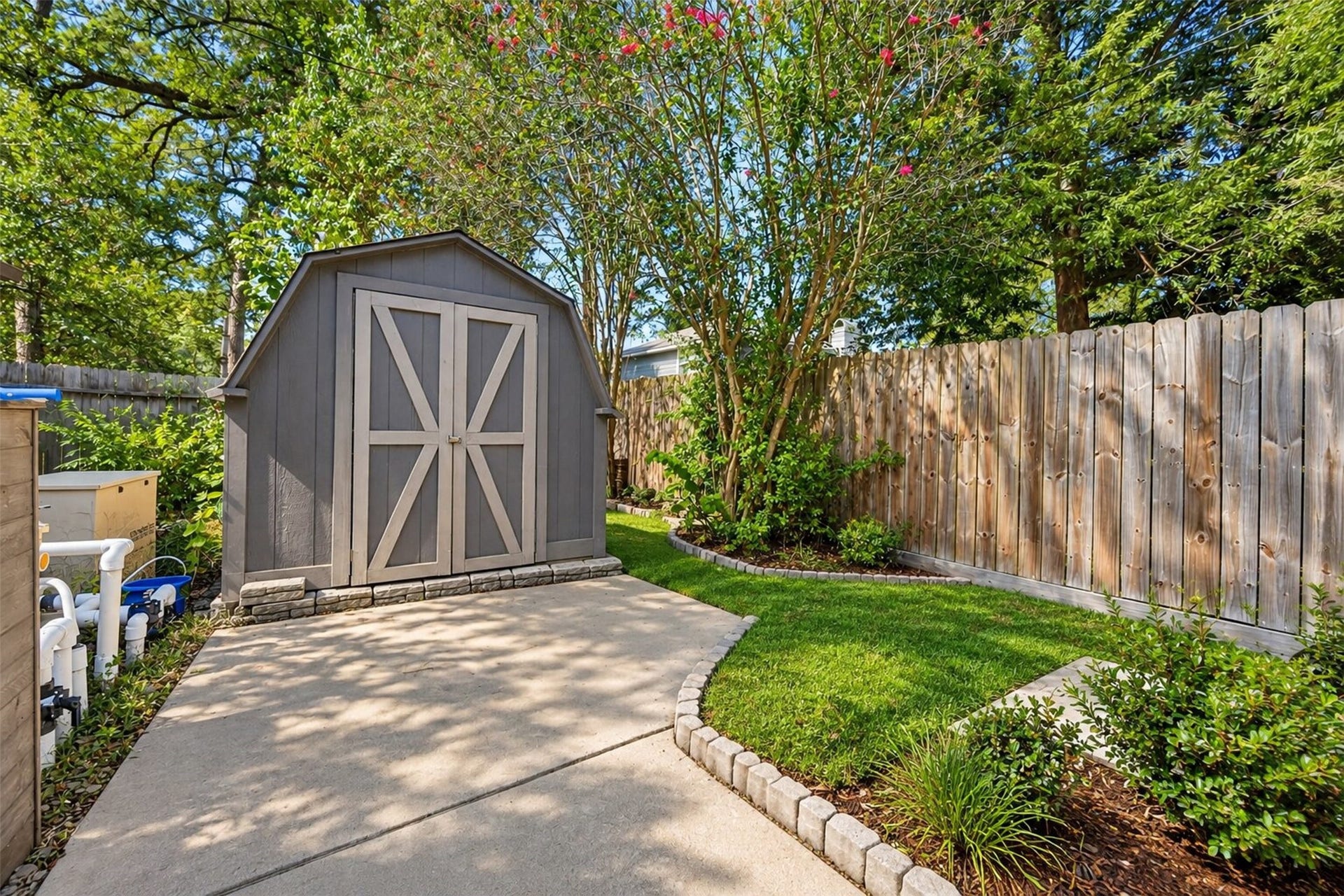 10818 Creektree Drive, Houston, TX 77070 Backyard Storage: Convenient outdoor storage shed surrounded by mature landscaping, a privacy fence, and a paved walkway for easy access.