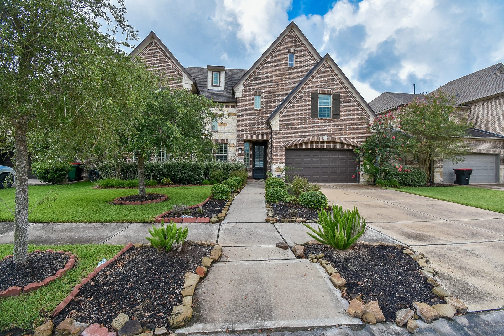 10106 Cypress Path, Missouri City, TX 77459 This gorgeous home has a charming brick exterior with a double-gabled roof and a two-car garage. The front yard is well-maintained with lush greenery, mature trees, and a welcoming walkway. Nice curb appeal and a spacious driveway.