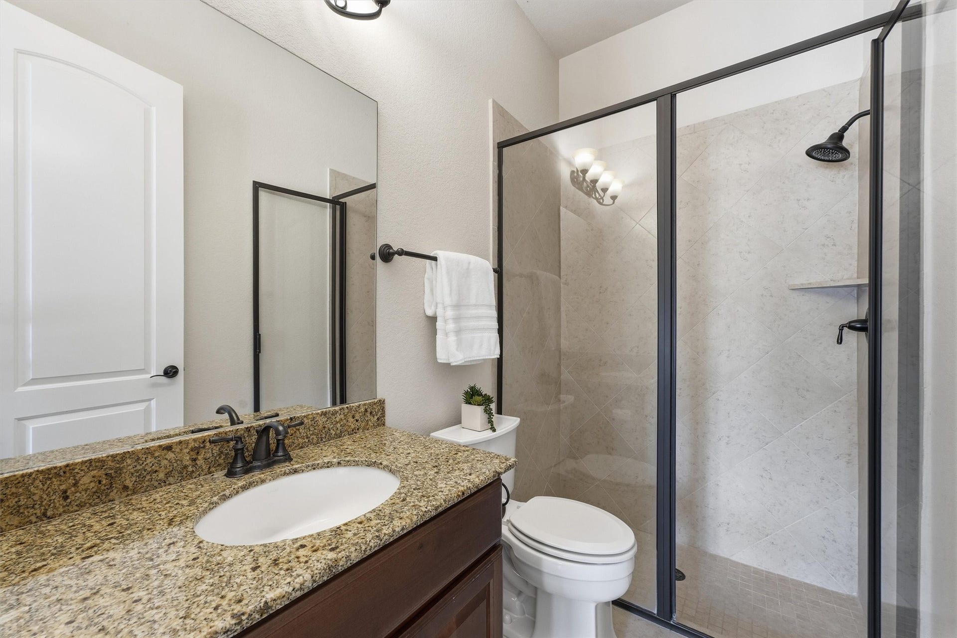 51 S Fremont Ridge Loop, Spring, TX 77389 The downstairs bedrooms private ensuite bath features a granite-topped vanity and glass-enclosed walk-in shower.