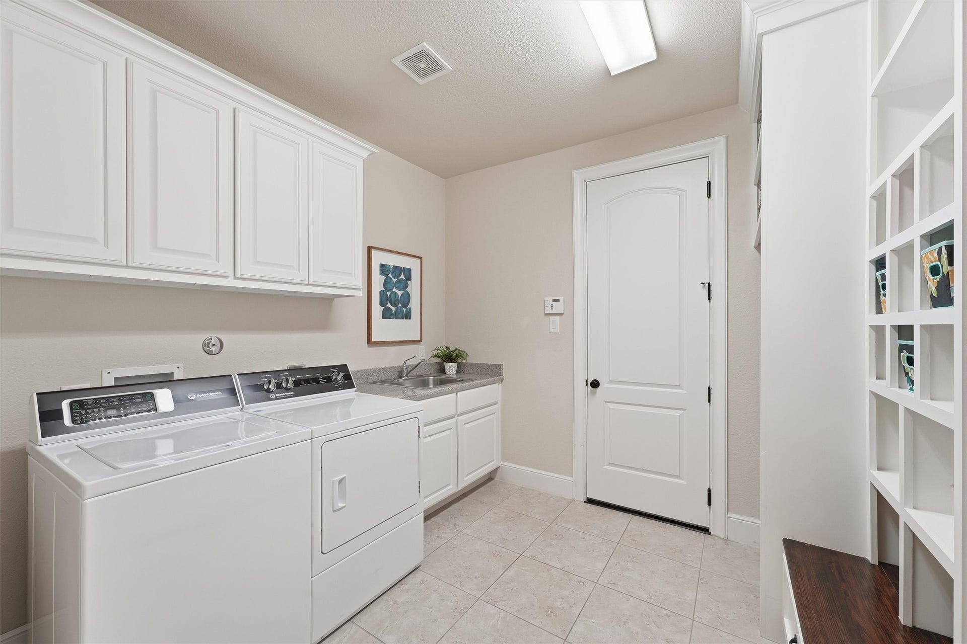 51 S Fremont Ridge Loop, Spring, TX 77389 The laundry room features ample cabinetry, a utility sink, and built-in storage cubbies with a bench.