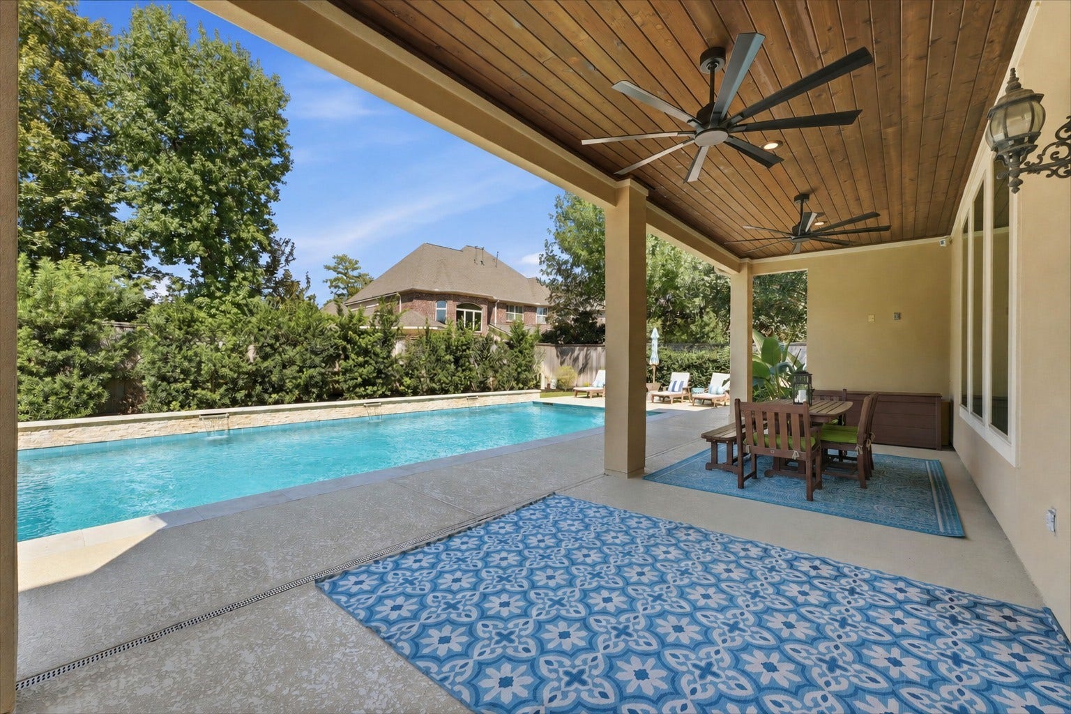 51 S Fremont Ridge Loop, Spring, TX 77389 One of two covered patios, this attached poolside retreat features an upgraded tongue-and-groove cedar ceiling, two 65-inch ceiling fans, and views of the pool and spa.