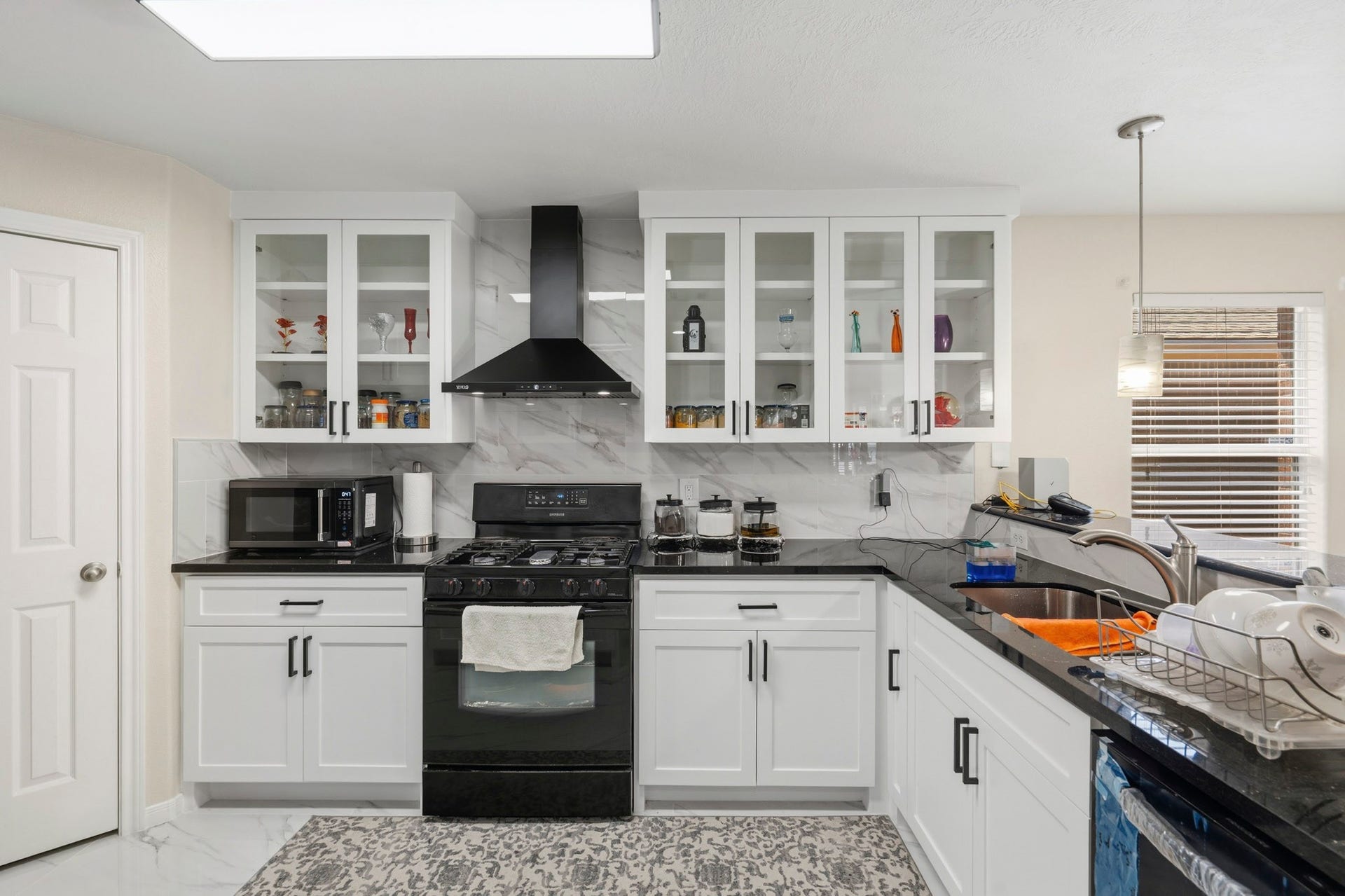 19302 Christine Crossing Drive, Richmond, TX 77407 Sleek finishes, glass-front cabinetry and a striking vent hood give the remodeled kitchen a fresh, polished look.