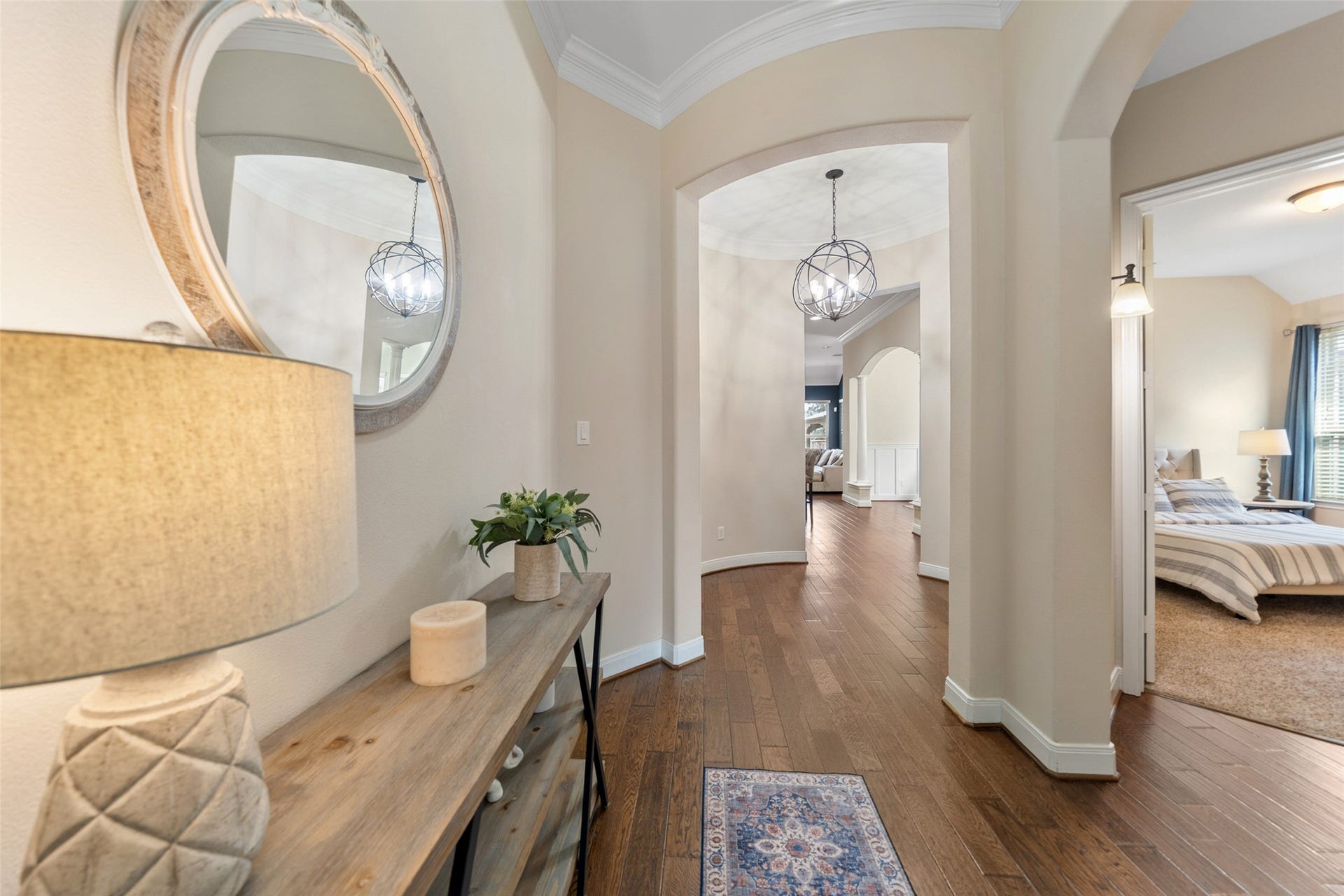 34 Danby Place, The Woodlands, TX 77375 The hallway leads to a bright living area, with warm hardwood floors, and a bedroom visible to the right, creating an inviting and functional layout.