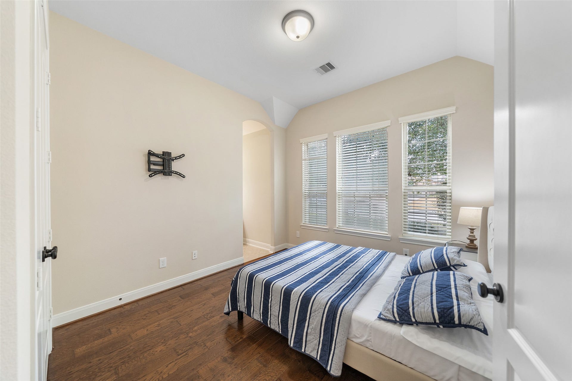 34 Danby Place, The Woodlands, TX 77375 Bright bedroom with hardwood floors and large windows letting in natural light, with soft and neutral color palette throughout.
