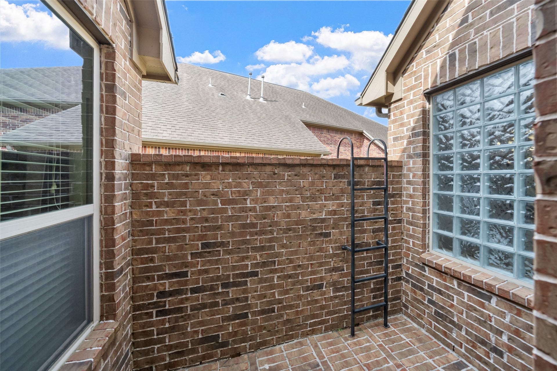34 Danby Place, The Woodlands, TX 77375 Enclosed brick and cozy private outdoor, adjacent to the kitchen area, features large windows, allowing natural light to enter.