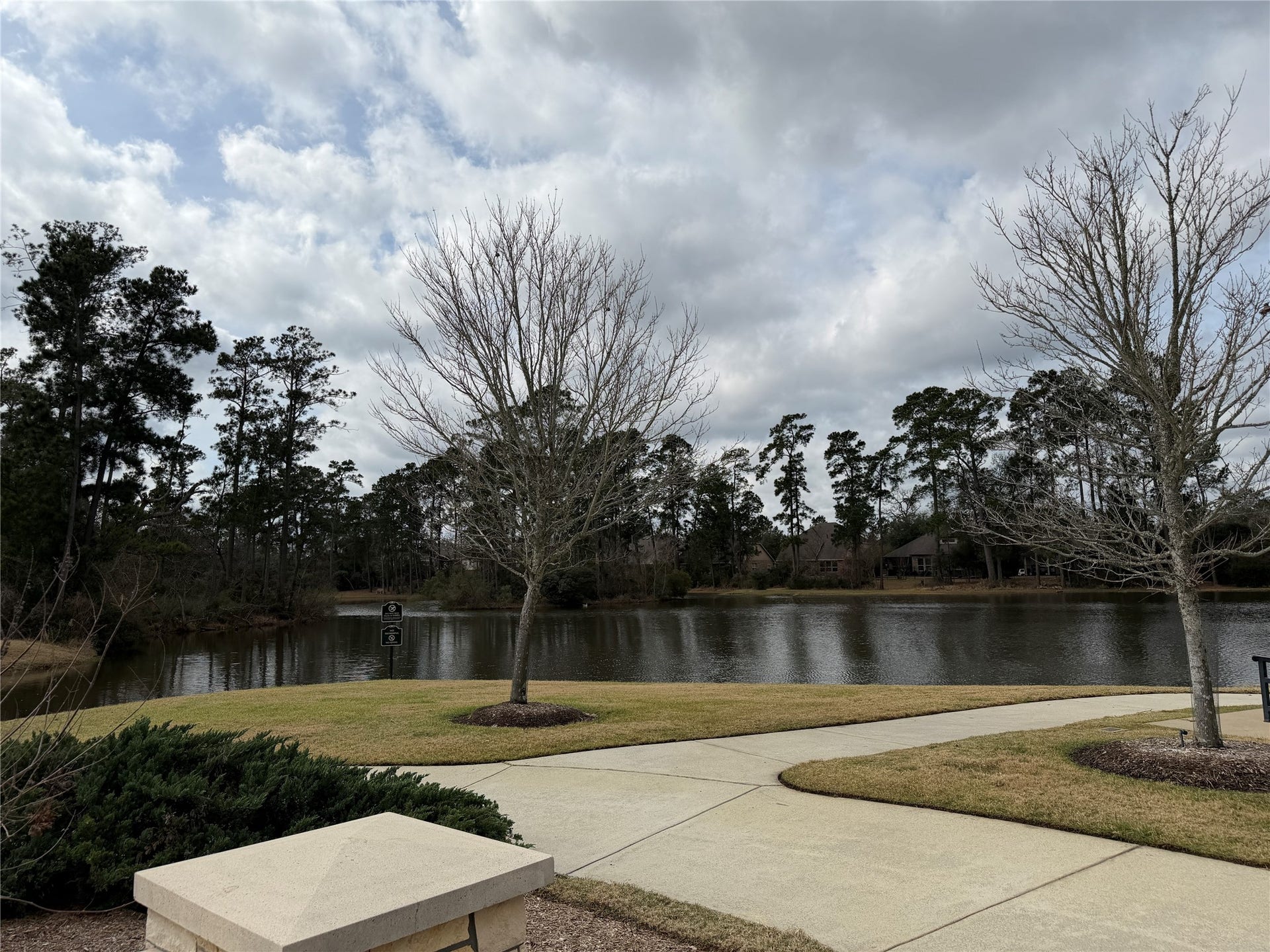 34 Danby Place, The Woodlands, TX 77375 Tranquil setting with a scenic pond view, surrounded by mature trees and a paved walkway, ideal for nature lovers seeking a peaceful neighborhood ambiance.