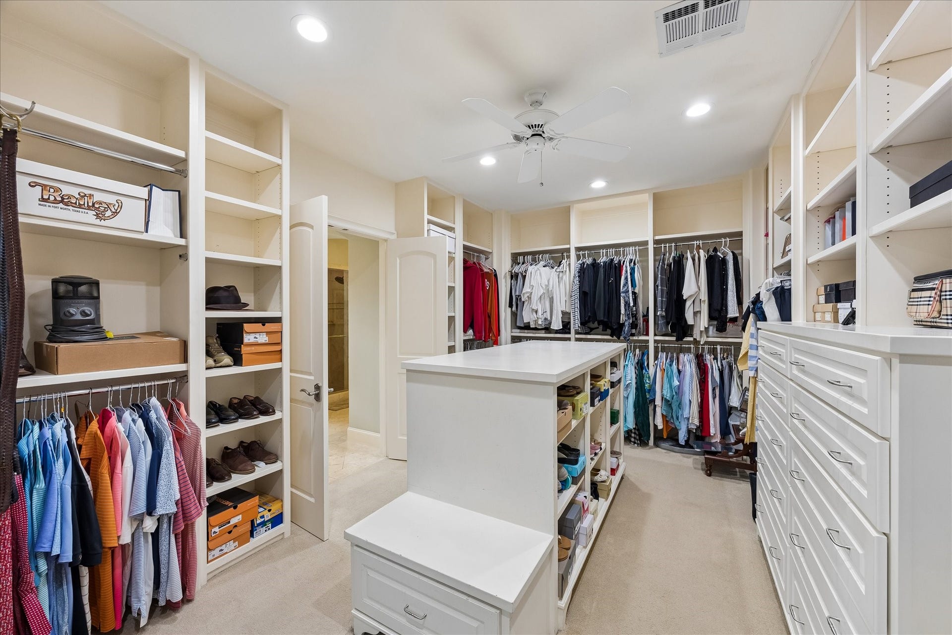 Oversized primary closet with ample hanging, built-ins and storage-filled island.