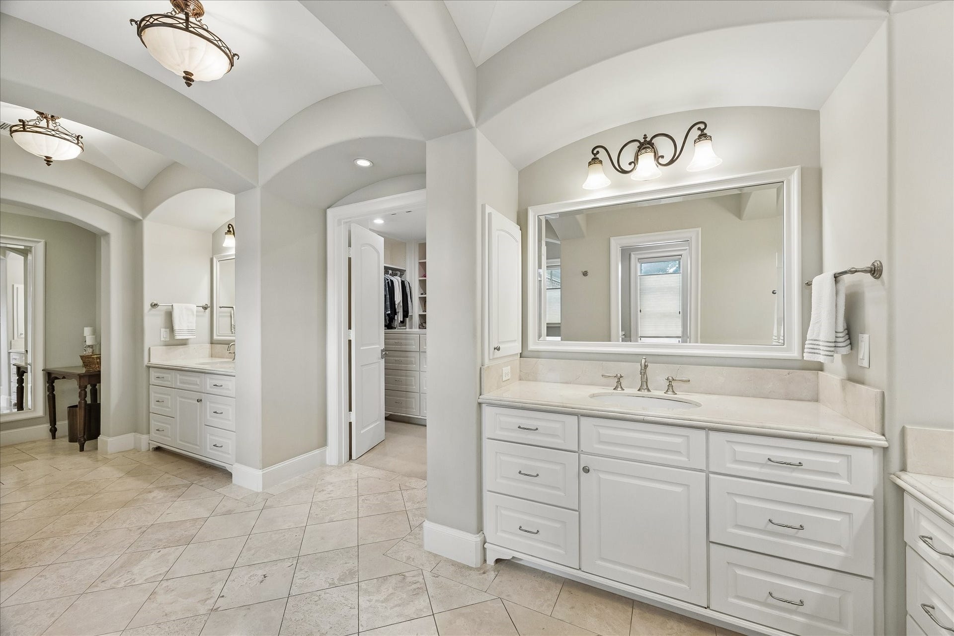 Spacious and neutral primary bath with marble counters.