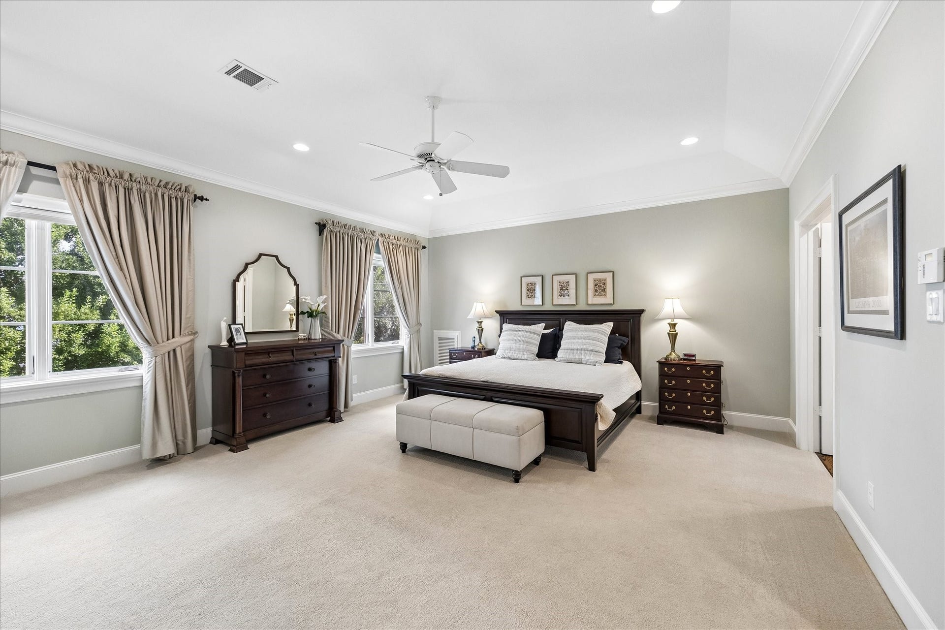 HUGE, light filled primary bedroom with vaulted ceilings, crown molding and drapery.