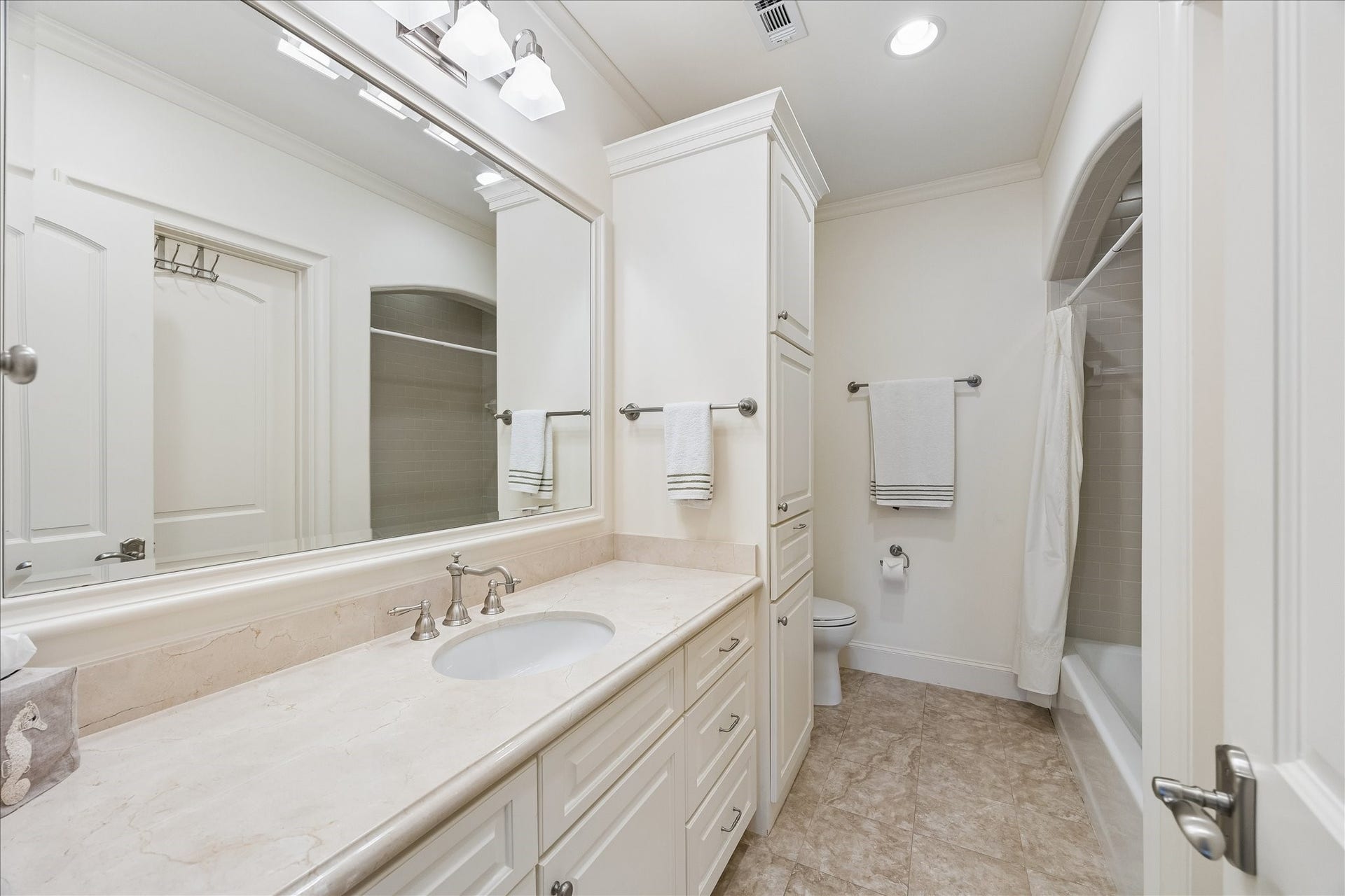 Nicely sized secondary en-suite bathroom with marble countertops, subway tile and shower/bath combo.