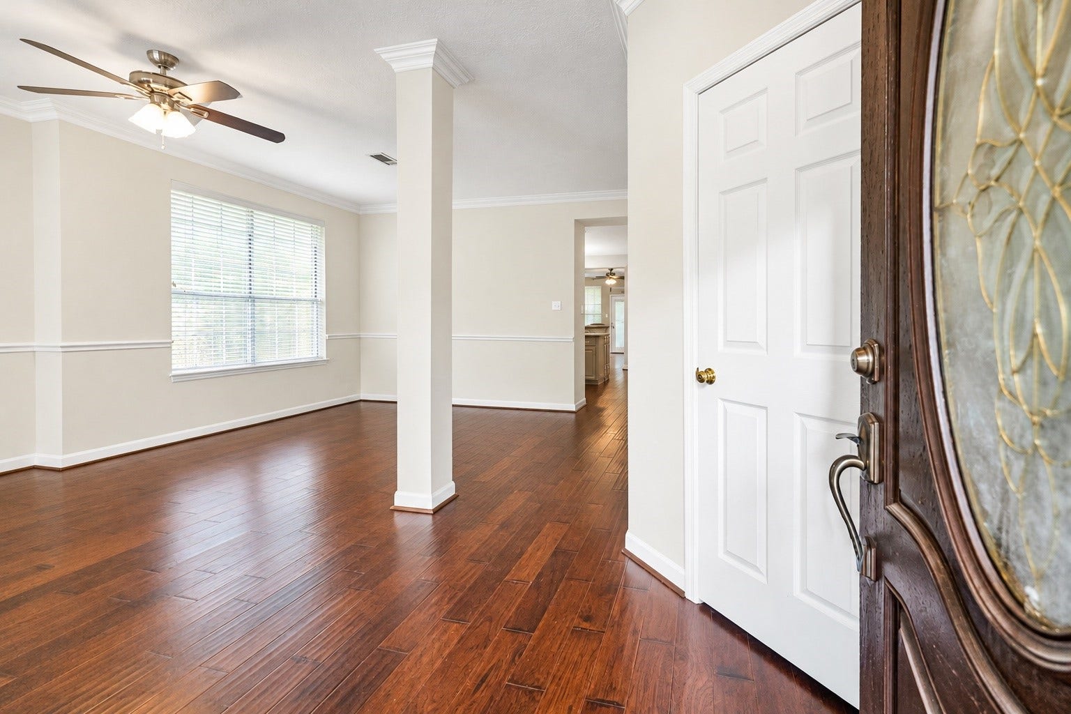 11 Sweetdream Place, The Woodlands, TX 77381 Inviting entryway with rich hardwood floors, elegant crown molding, and abundant natural light, leading to an open living space with a ceiling fan for comfort.