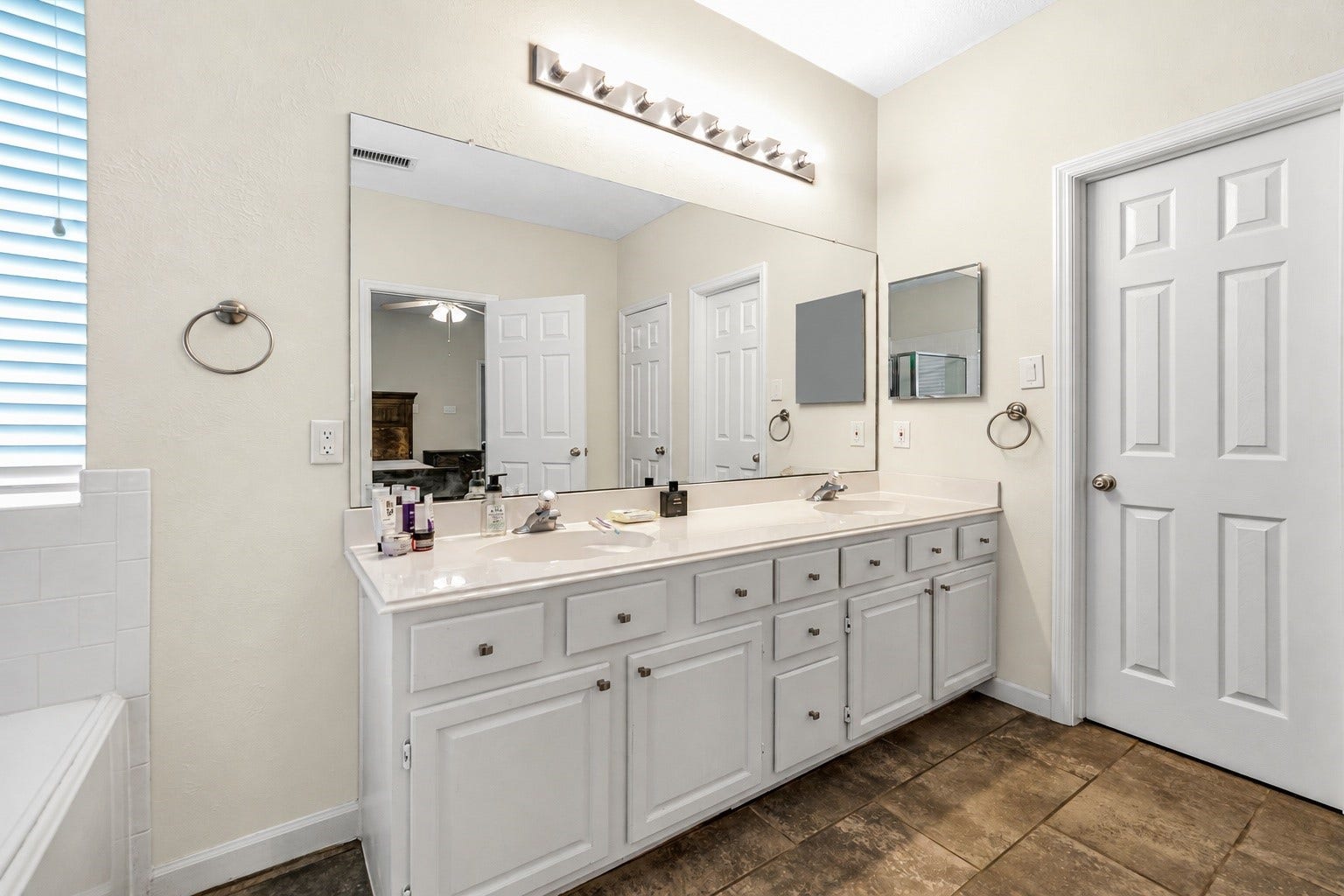 11 Sweetdream Place, The Woodlands, TX 77381 Spacious bathroom featuring dual sinks with ample counter space, plenty of storage in the white cabinetry, and a large mirror enhancing the room's brightness.