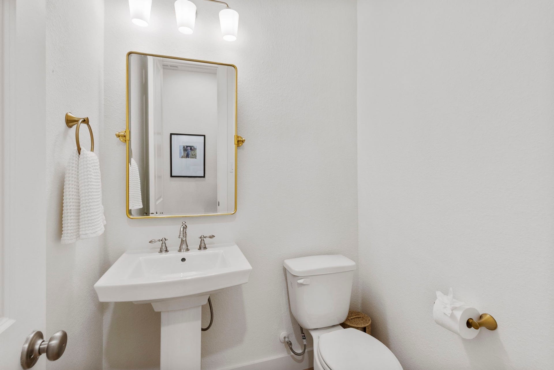18030 Blu Terrace Drive, Conroe, TX 77302 Bright half bath featuring a sleek pedestal sink, brushed-nickel faucet, and modern globe lighting.