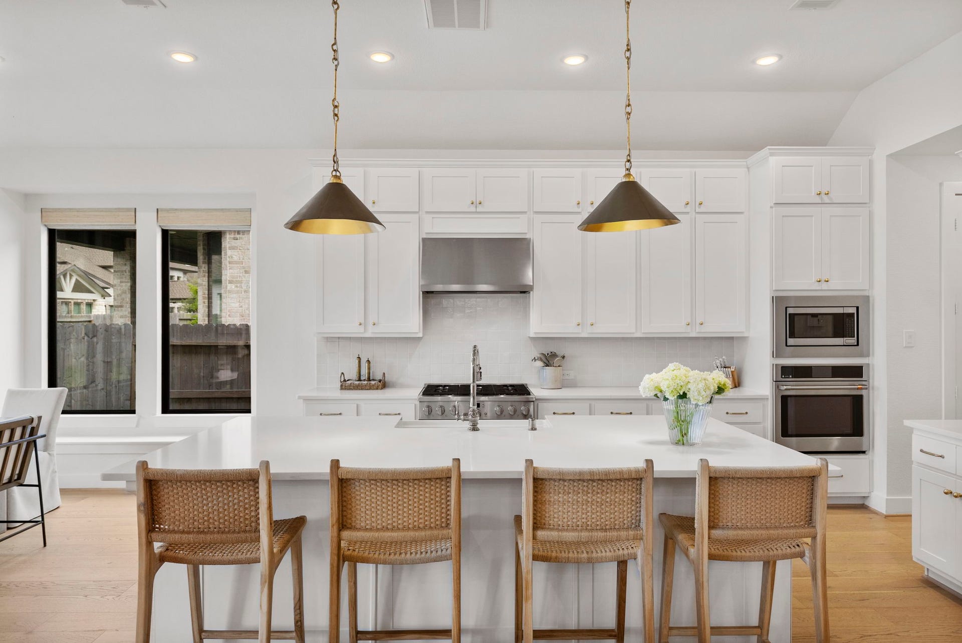 18030 Blu Terrace Drive, Conroe, TX 77302 Bright white kitchen with oversized island, designer pendants, built-in ovens, and expansive cabinetry for storage.