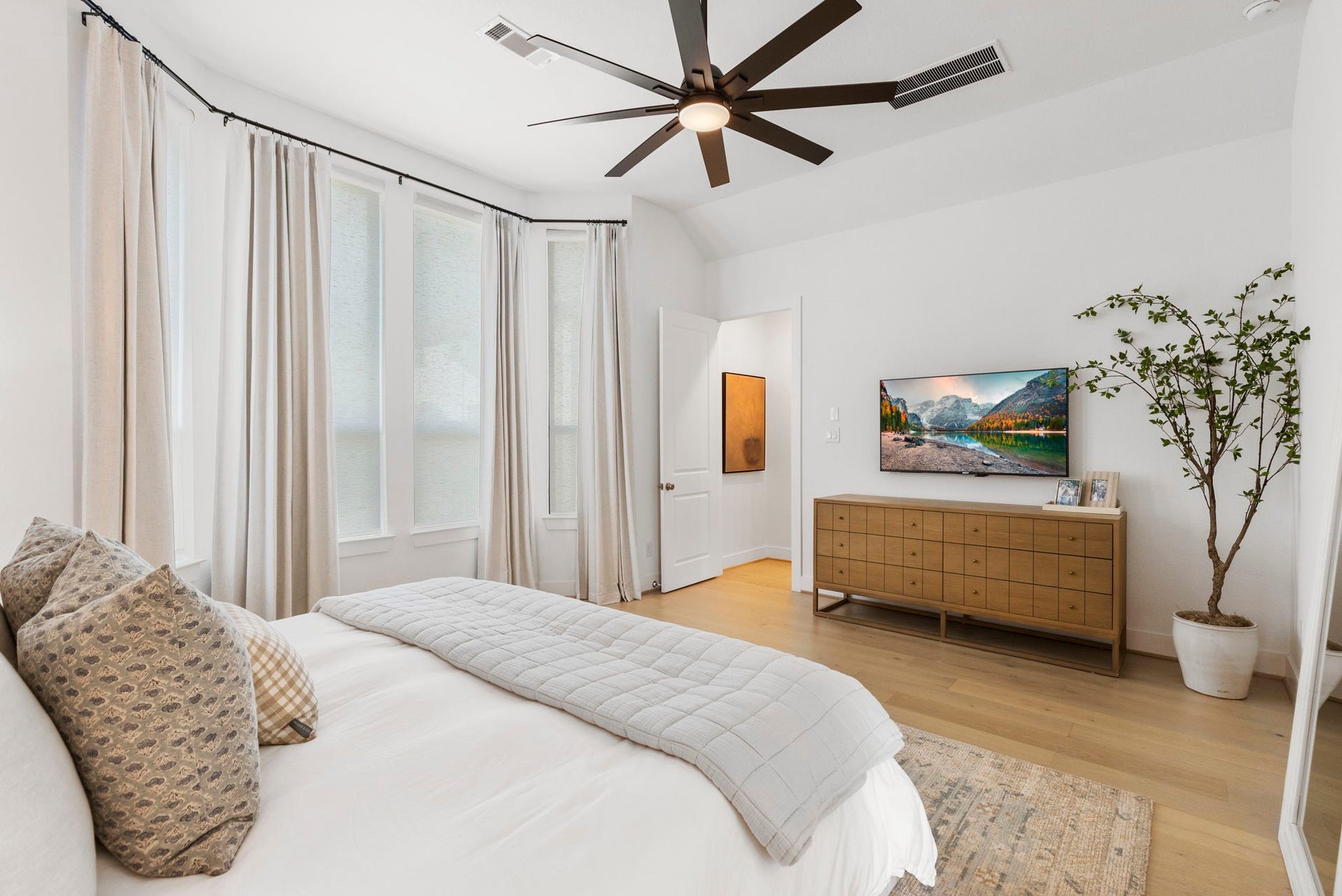 18030 Blu Terrace Drive, Conroe, TX 77302 Airy bedroom featuring bay windows, wide-plank hardwood floors, and sleek designer ceiling fan lighting.