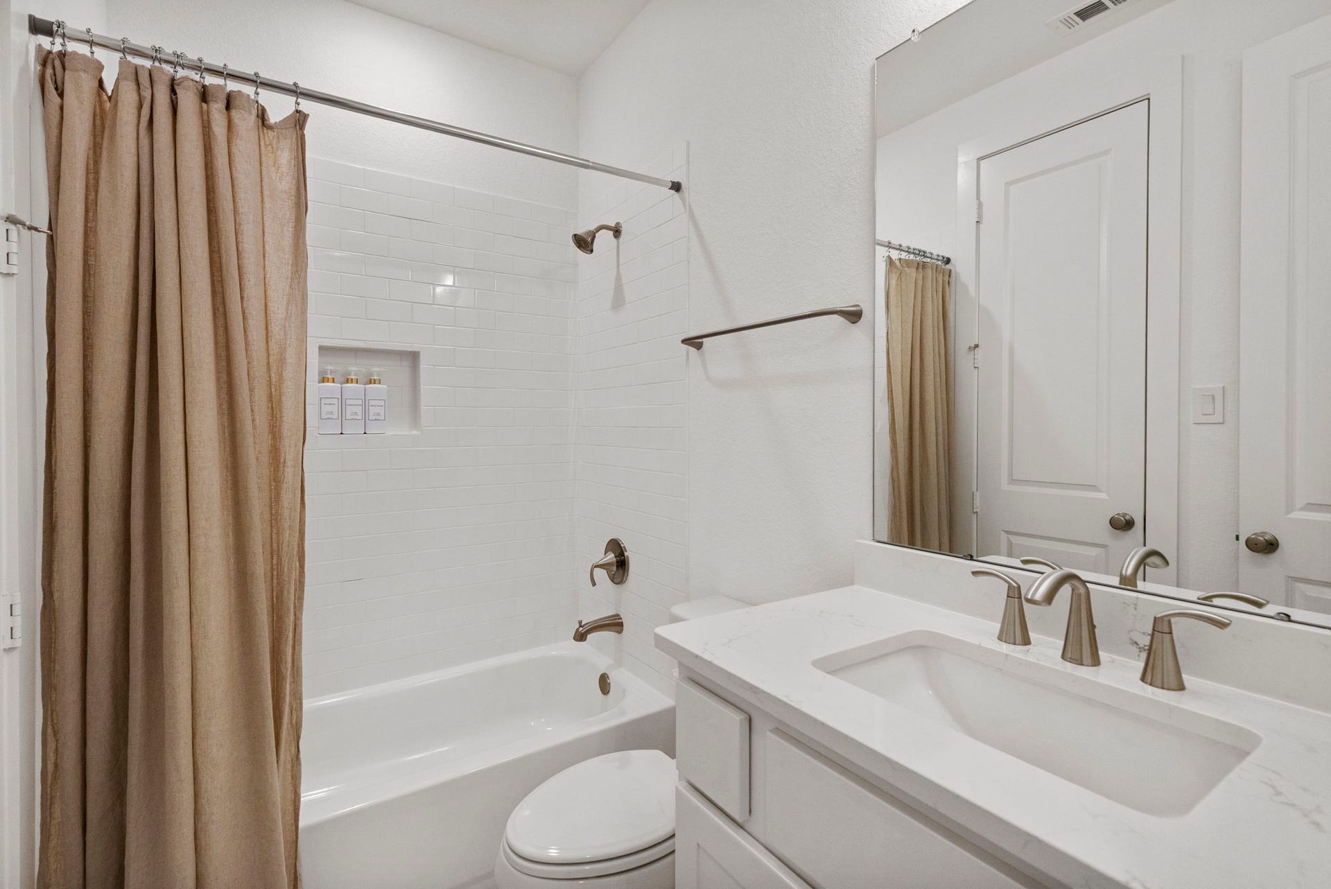 18030 Blu Terrace Drive, Conroe, TX 77302 Bright bathroom featuring a subway-tile tub surround, quartz vanity, and oversized mirror with sleek fixtures.