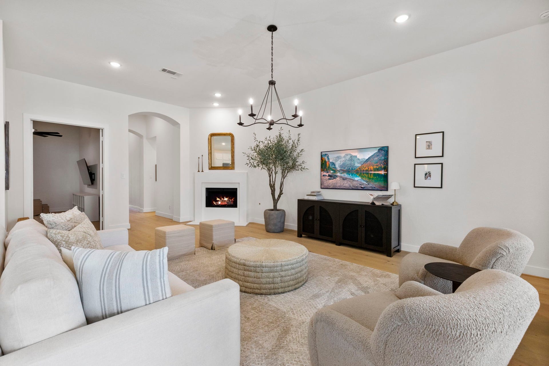 18030 Blu Terrace Drive, Conroe, TX 77302 Sunlit open living room with hardwood floors, modern chandelier, and tall picture windows overlooking the patio.