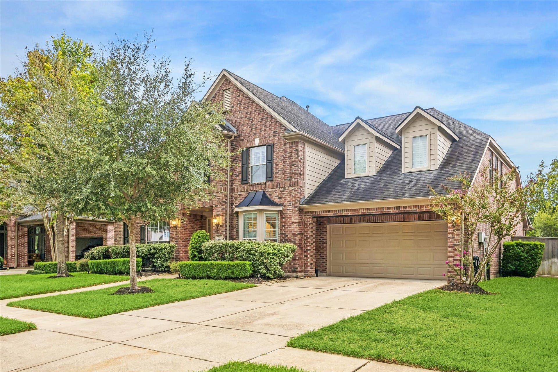 7922 EMERALD HAVEN DRIVE, Sugar Land, TX 77479 CLASSIC BRICK ELEVATION WITH DORMER WINDOWS, A COVERED ENTRY, AND A WIDE DRIVEWAY LEADING TO THE TWO-CAR GARAGE.