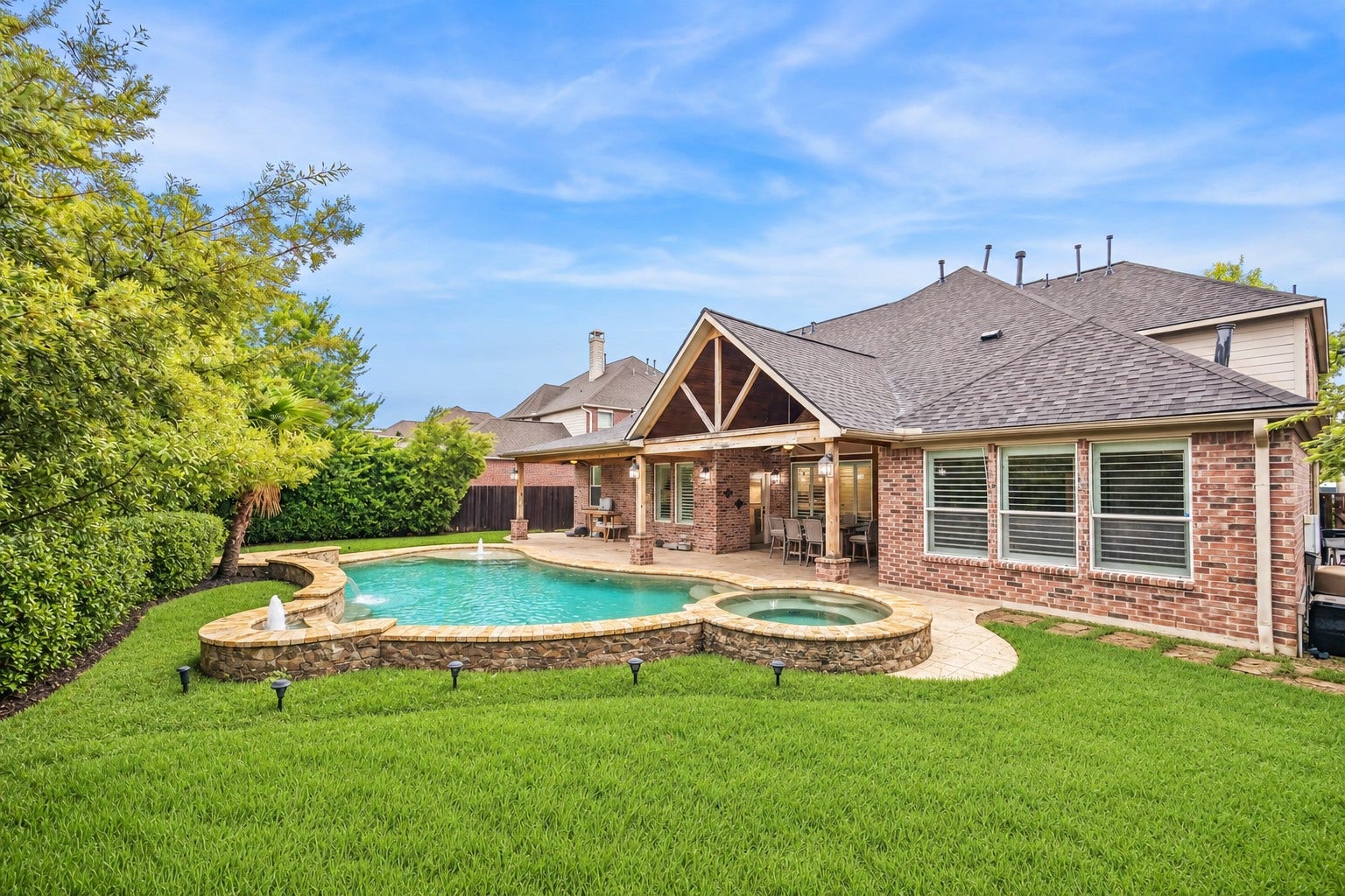 7922 EMERALD HAVEN DRIVE, Sugar Land, TX 77479 PRIVATE BACKYARD WITH A POOL AND SPA, COVERED OUTDOOR LIVING AREA, MATURE LANDSCAPING, AND GREEN LAWN SPACE.