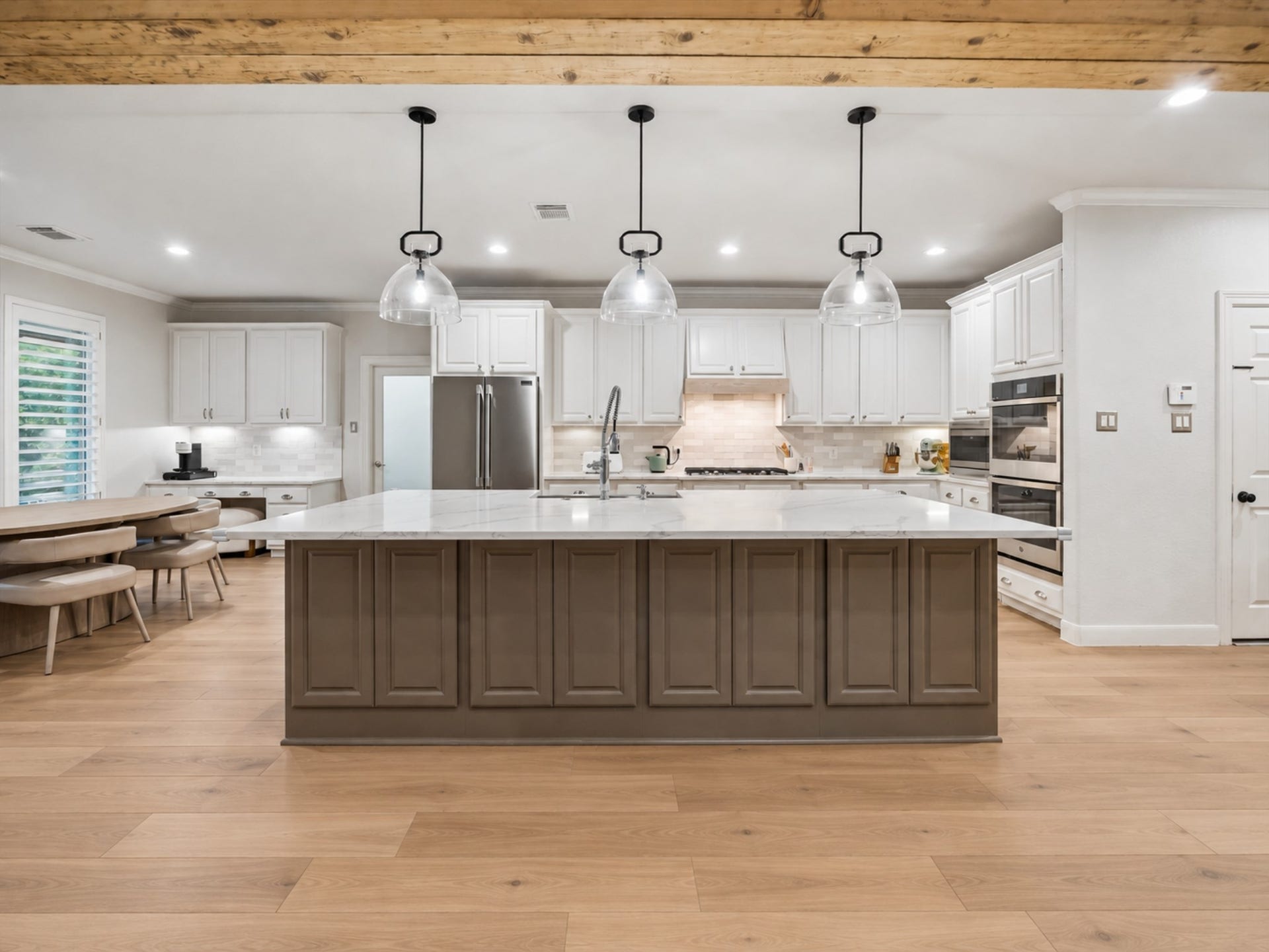 7922 EMERALD HAVEN DRIVE, Sugar Land, TX 77479 SPACIOUS KITCHEN WITH AN OVERSIZED ISLAND, ABUNDANT CABINETRY, QUARTZ-STYLE COUNTERS, AND THREE PENDANT LIGHTS.