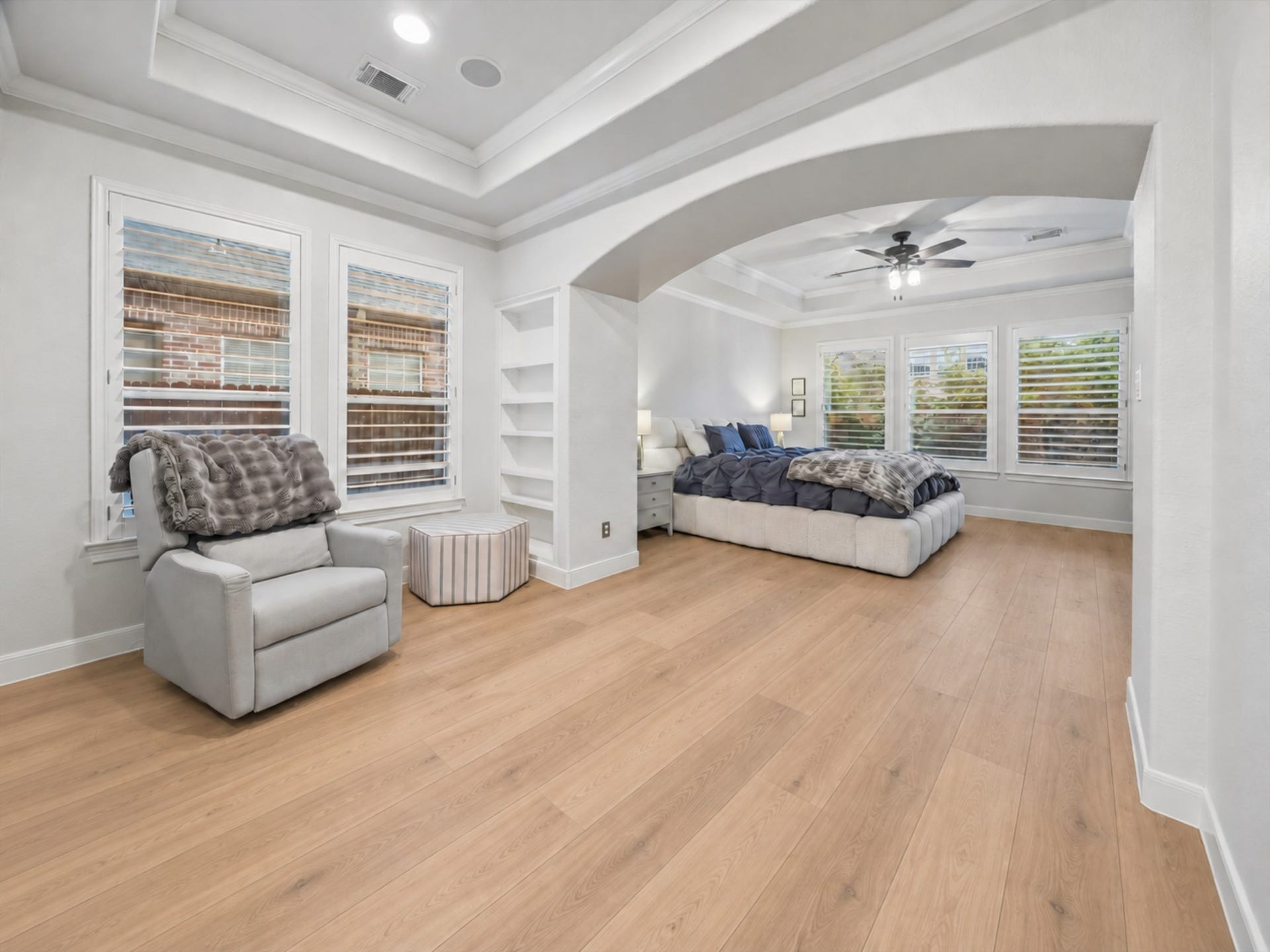 7922 EMERALD HAVEN DRIVE, Sugar Land, TX 77479 SPACIOUS PRIMARY SUITE WITH HARDWOOD FLOORING, A TRAY CEILING, BUILT-IN SHELVING, AND A WALL OF WINDOWS WITH PLANTATION SHUTTERS.