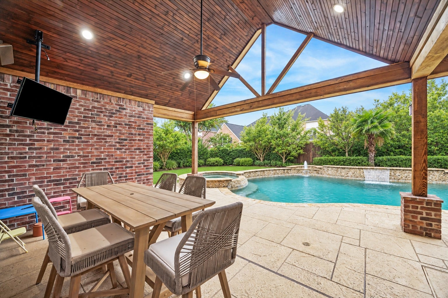 7922 EMERALD HAVEN DRIVE, Sugar Land, TX 77479 EXPANSIVE COVERED PATIO WITH A VAULTED WOOD CEILING, EXPOSED BEAMS, RECESSED LIGHTING, AND A CEILING FAN.