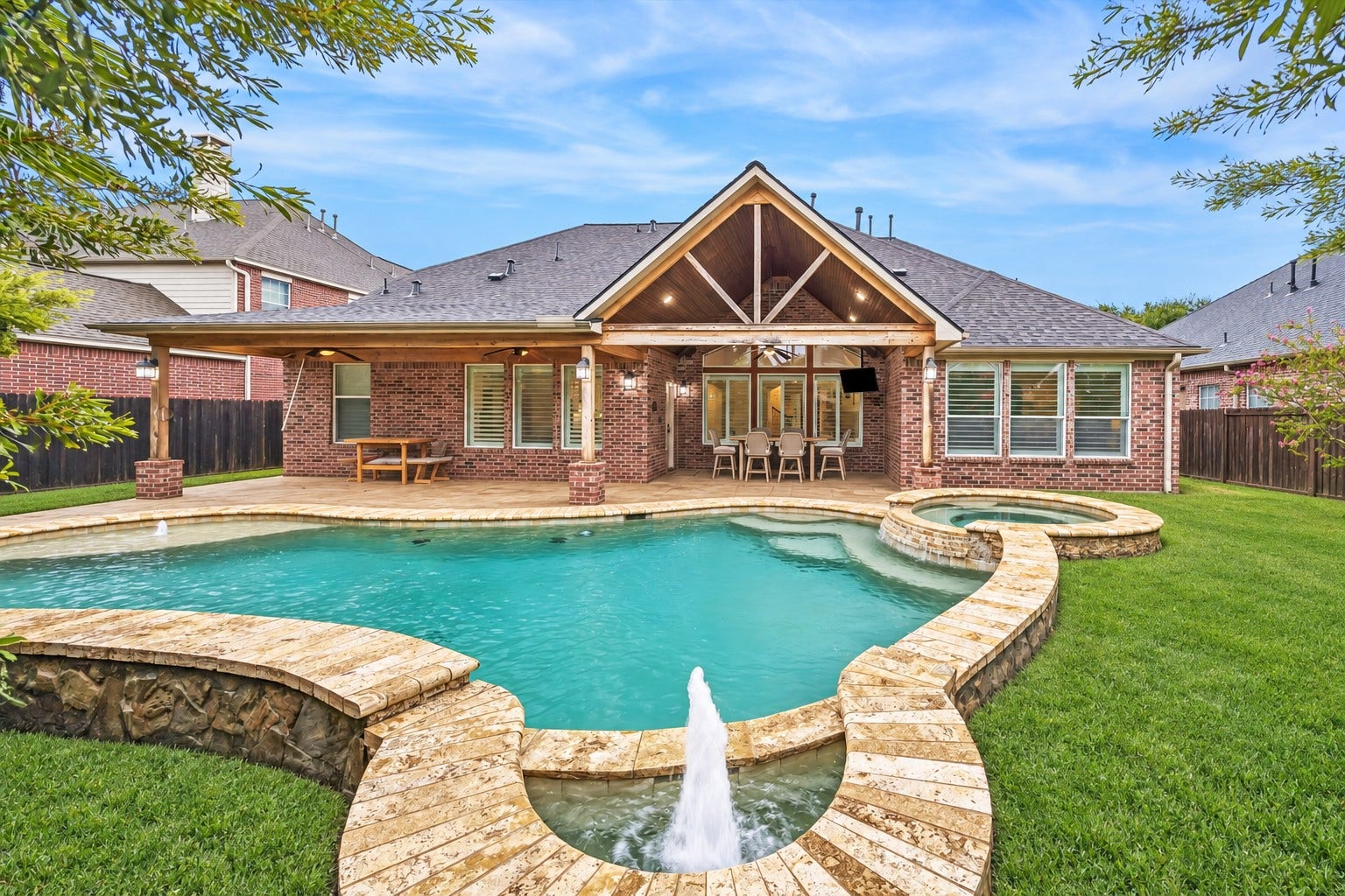 7922 EMERALD HAVEN DRIVE, Sugar Land, TX 77479 RESORT-STYLE POOL WITH AN ATTACHED RAISED SPA, MULTIPLE WATER FEATURES, AND STONE COPING.