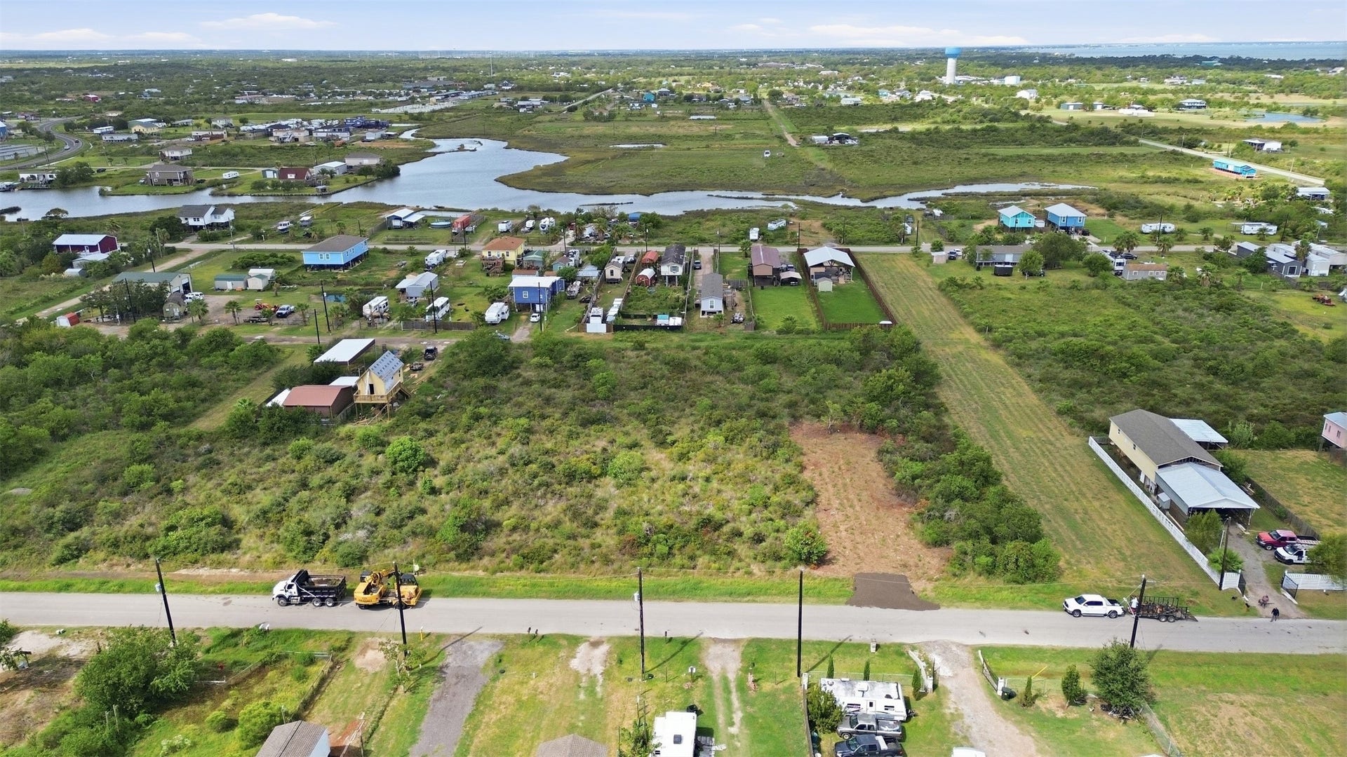 17 W Street, San Leon, TX 77539 Low-angle aerial from the road. A water tower and the broader community are visible in the distance, which shows how established the area is.
