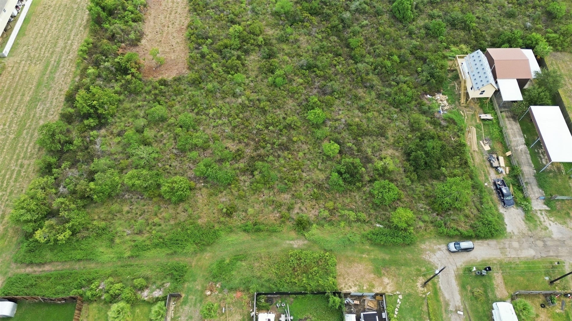 17 W Street, San Leon, TX 77539 Overhead view of the lot covered in native coastal brush and scattered trees. A cleared section is visible along the front.