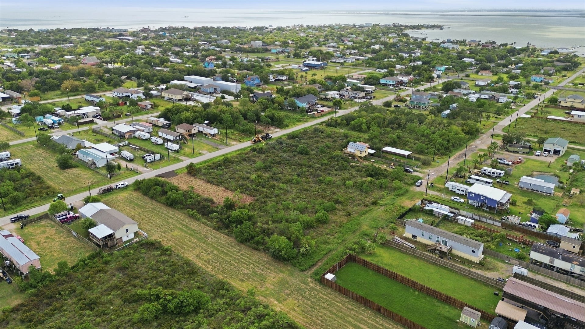 17 W Street, San Leon, TX 77539 Angled aerial showing the full tract, with the bay on the horizon. Surrounding lots hold a mix of stilted coastal homes and cottages.