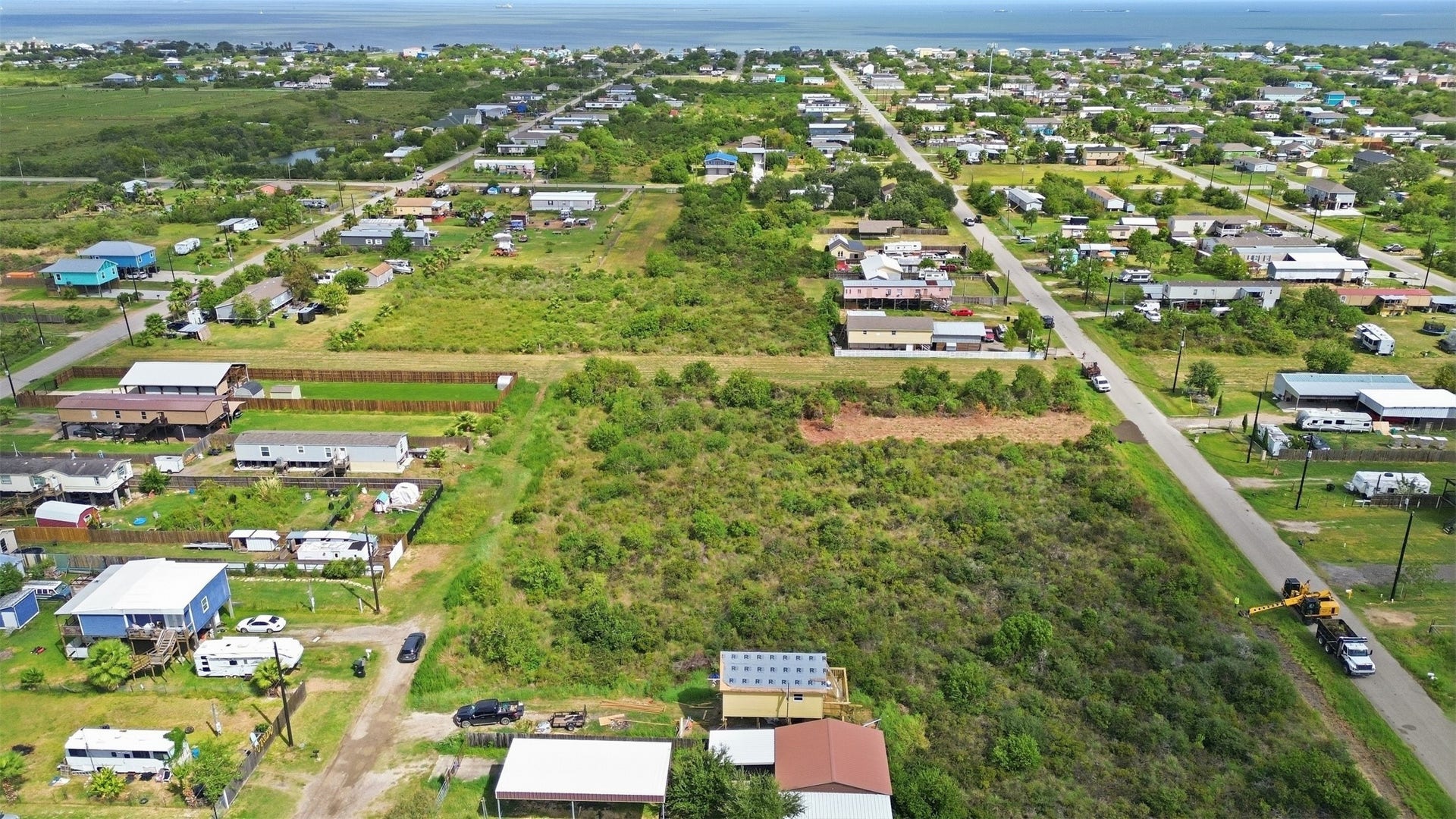 17 W Street, San Leon, TX 77539 View from the back of the tract toward the road. It shows the lot's depth, the neighboring homes, and the bay in the distance.