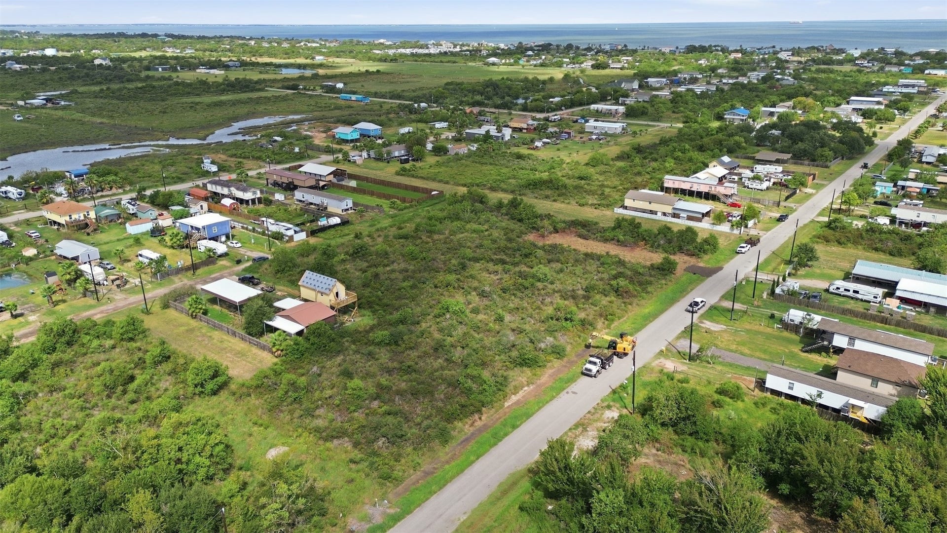 17 W Street, San Leon, TX 77539 View along the paved street with open marsh and tidal water on one side and the bay on the horizon. Neighboring lots are developed with homes and outbuildings.