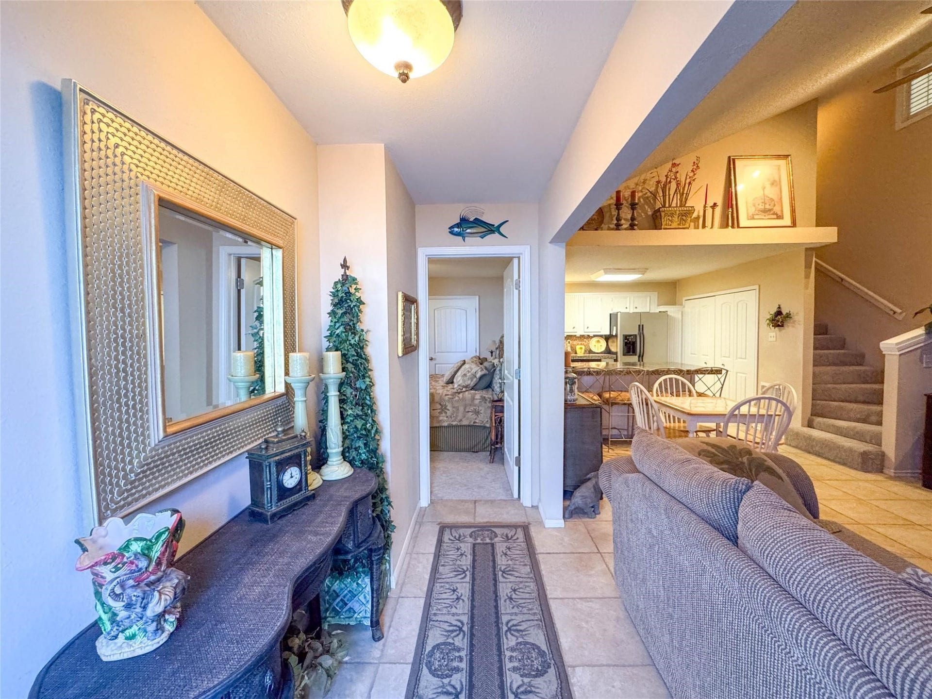 1031 Redfish Street, Bayou Vista, TX 77563 This welcoming entryway features a cozy living space with neutral tones and tile flooring. It opens into a kitchen and dining area with ample natural light. A staircase leads upstairs, providing easy access to additional rooms.