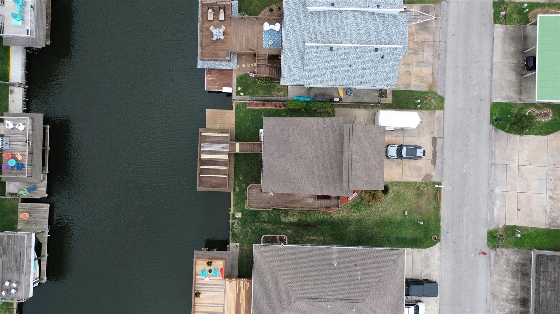 1031 Redfish Street, Bayou Vista, TX 77563 This aerial photo showcases a waterfront property with a private dock, situated along a canal. The home features a spacious outdoor deck, and the surrounding neighborhood appears well-maintained, with nearby homes also having access to the water.