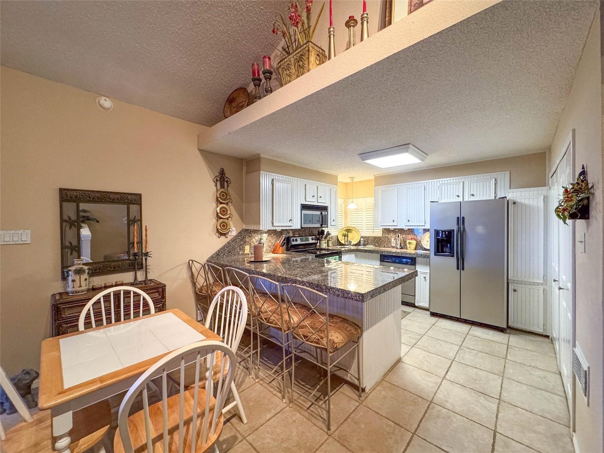 1031 Redfish Street, Bayou Vista, TX 77563 This kitchen features a spacious layout with a central island, granite countertops, and stainless steel appliances. It offers ample cabinet storage, a cozy dining area, and decorative accents for a welcoming atmosphere.