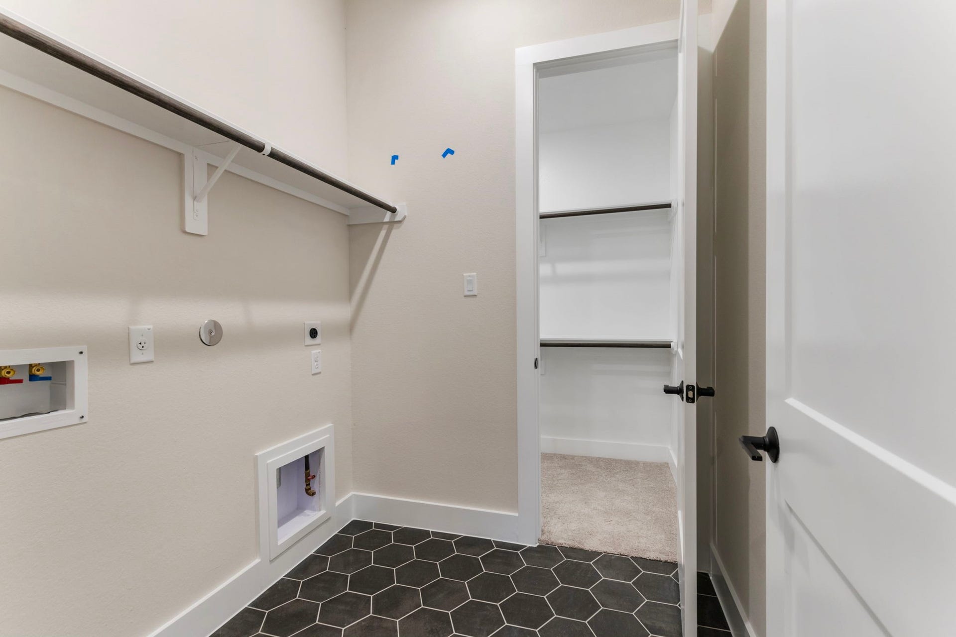 8143 Fenway Heights Dr, The Woodlands, TX 77389 Modern laundry room with sleek hexagonal tile flooring, ample shelving, and direct access to primary bedroom closet.