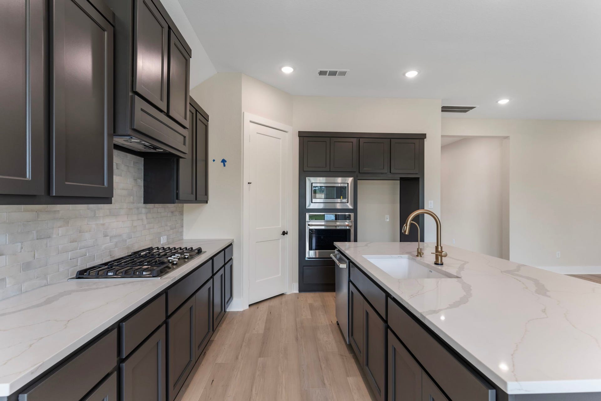 8143 Fenway Heights Dr, The Woodlands, TX 77389 Sleek modern kitchen features dark cabinetry, a spacious quartz island with a built-in sink, and stainless steel appliances. Refrigerator is not pictured!!